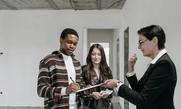 agent man signs document couple property real estate