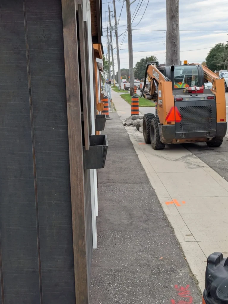 Who Is Paying for Oshawa Sidewalk Work at 109 Bloor Street East? Broken sidewalk concrete and a construction worker near 109 Bloor Street East in Oshawa