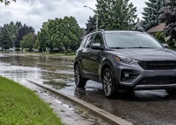 A vehicle stopped safely beside a flooded suburban road after heavy rain