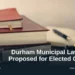 Illustrative stock photo: Books and an open notebook on a desk. Photo by Mikhail Pavstyuk on Unsplash. Headline: Durham Municipal Law Exam Proposed for Elected Officials. AllAboutDurham.com.