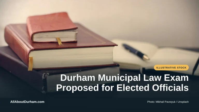 Illustrative stock photo: Books and an open notebook on a desk. Photo by Mikhail Pavstyuk on Unsplash. Headline: Durham Municipal Law Exam Proposed for Elected Officials. AllAboutDurham.com.