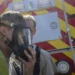 File photo: Two firefighters in protective suits, one helping the other adjust a respirator mask, in front of a fire truck during a hazardous materials training exercise. Representative image; does not show the Uxbridge exercise.