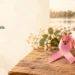 Original editorial still life of a pink ribbon, paper hearts and a tea cup, symbolizing community support; not a photograph of Adrienne Wilson.